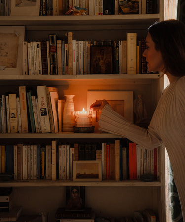 MaCenna Lee, of XO MaCenna, lights the Arlow candle as it sits nestled in a bookshelf.