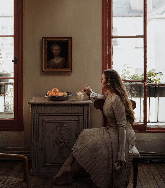 MaCenna Lee, of XO MaCenna, is sitting as she lights the Arlow candle by Auden Lueur.