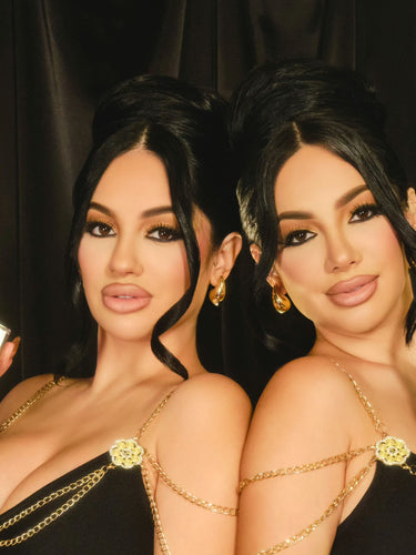 Brittany and Briana Murillo pose back to back, each holding a bottle of the Second Self Eau de Parfum from the Murillo Twins Fragrance.