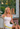 Tracy Anderson seated in a chair, holding the Tracy Anderson Fragrance Spring Break Sweat Eau de Parfum.