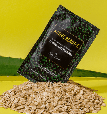 The best cleansing and exfoliating wipes placed on top of a pile of oats in front of an aloe leaf.