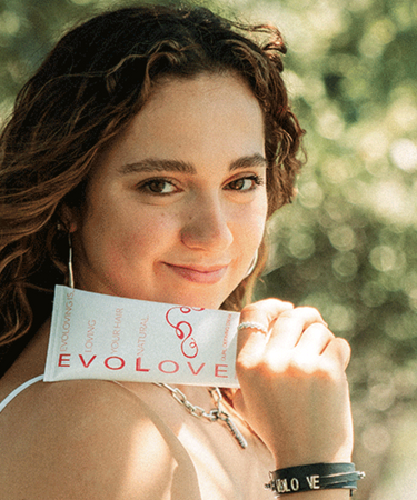 Professional dancer, Kaycee Rice, standing outside holding her curl cream for wavy and frizzy hair.