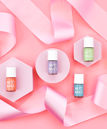 Six nail polishes displayed against a pink wall with pink ribbon draped around the polishes.